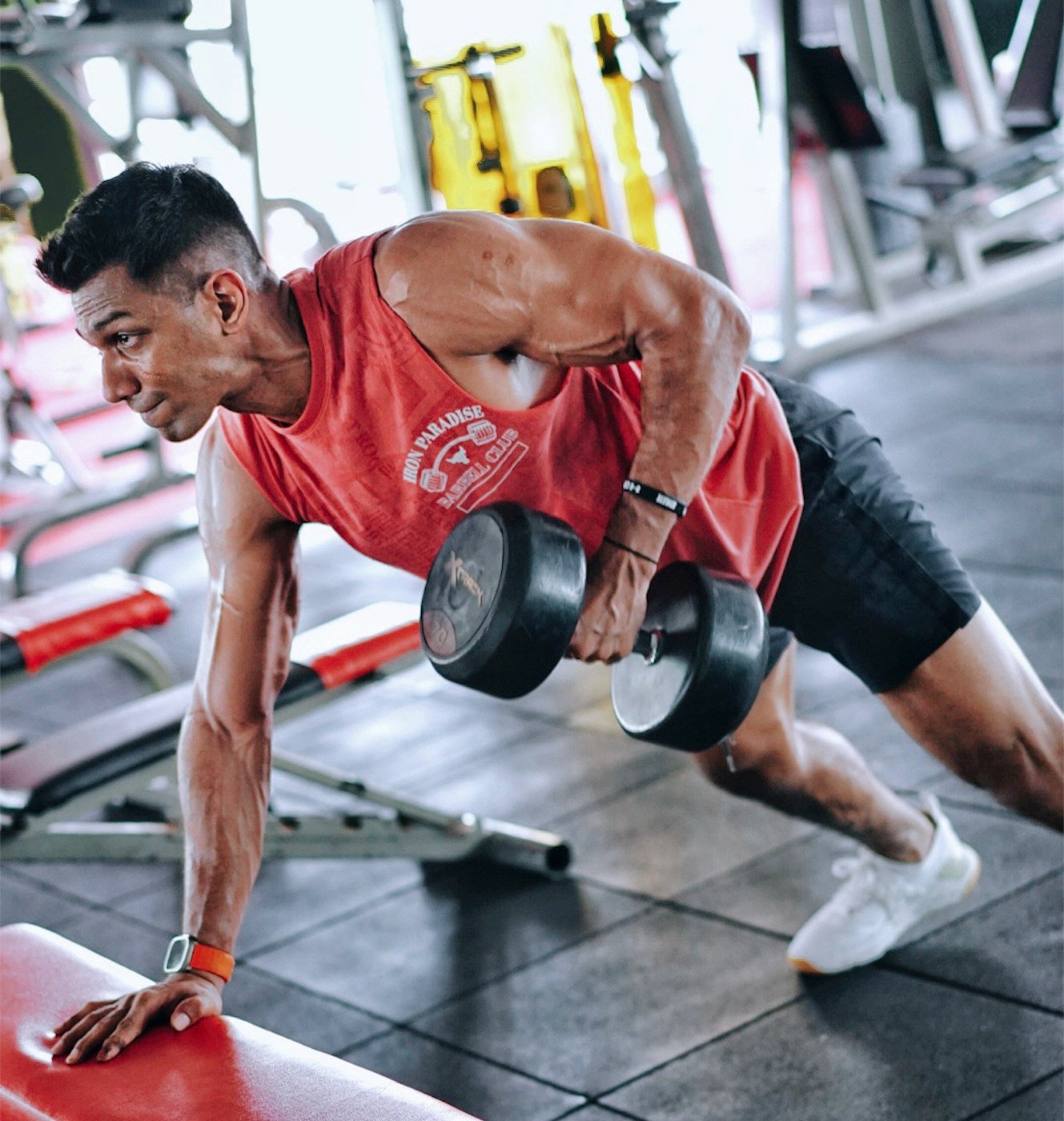 Theebaan G performing a single-arm dumbbell row in the gym